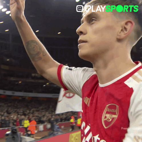 A Man In A Red And White Arsenal Jersey Waves His Hand GIF