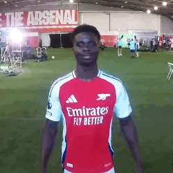 A Man In A Red And White Emirates Fly Better Soccer Jersey Is Standing On A Field . GIF