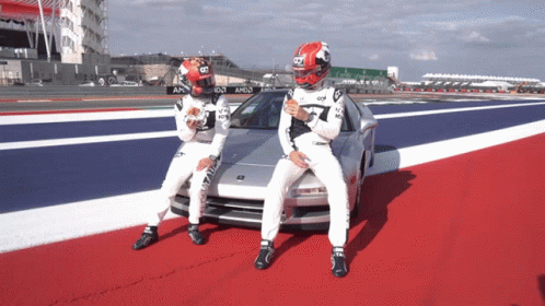 a man in a red and white helmet stands next to another man in a white suit
