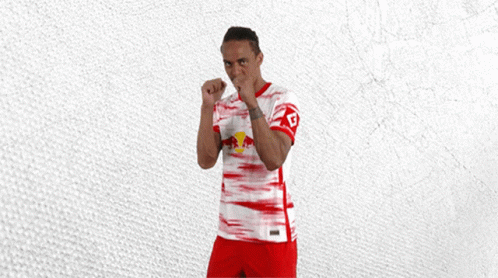 A Man In A Red And White Jersey With A Red Bull On The Front GIF