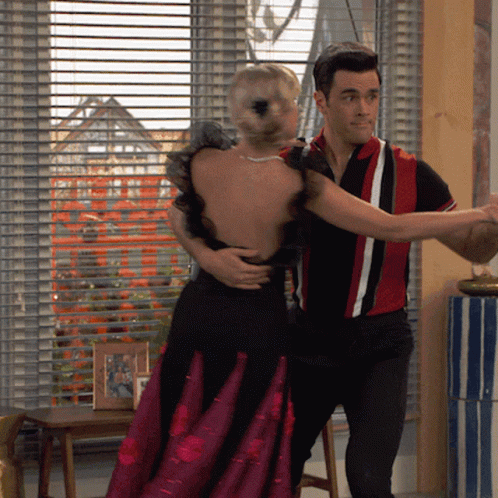 A Man In A Red And White Shirt Is Dancing With A Woman In A Black Dress GIF