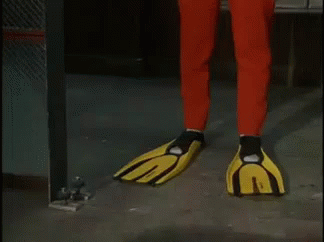 A Man In A Red And Yellow Superhero Costume Is Standing In A Room . GIF
