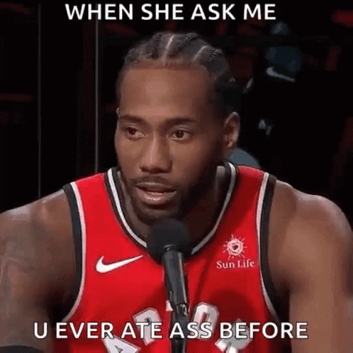 a man in a red basketball jersey is talking into a microphone .