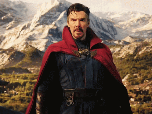 A Man In A Red Cape Stands In Front Of A Snowy Mountain GIF