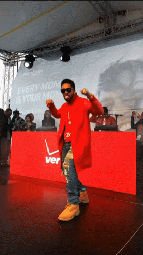 A Man In A Red Coat Is Dancing In Front Of A Sign That Says Verizon GIF