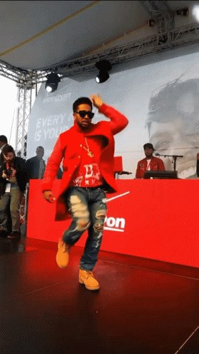 A Man In A Red Coat Is Dancing In Front Of A Verizon Sign GIF