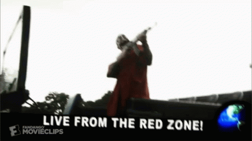 a man in a red coat is holding a gun in front of a car that says `` we from the red zone '' .