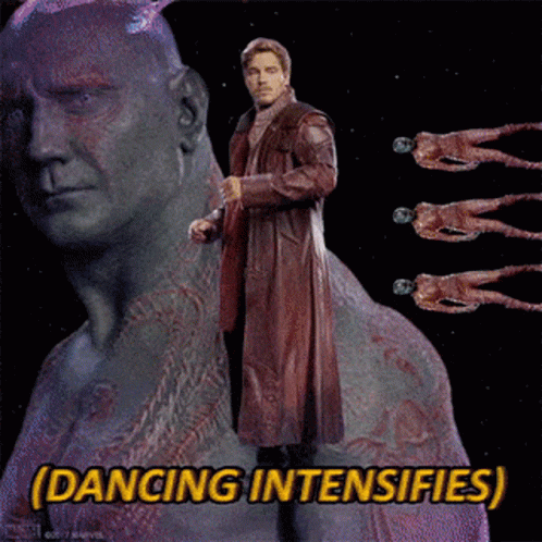 A Man In A Red Coat Is Standing In Front Of A Statue With The Words Dancing Intensifies Below Him GIF