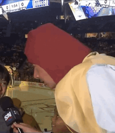 A Man In A Red Hat Is Being Interviewed By A Snv Reporter . GIF