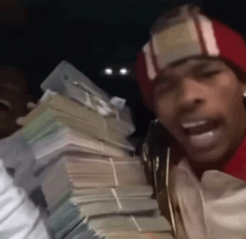 A Man In A Red Hat Is Holding A Large Pile Of Money . GIF