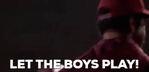 A Man In A Red Hat Is Standing In Front Of A Sign That Says `` Let The Boys Play ! '' GIF