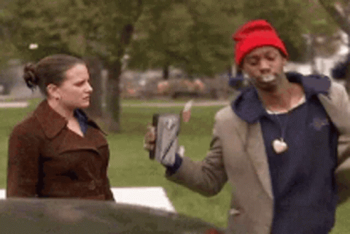 A Man In A Red Hat Is Talking To A Woman In A Brown Coat GIF