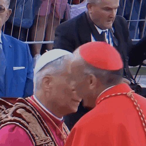 A Man In A Red Hat Talks To Another Man GIF