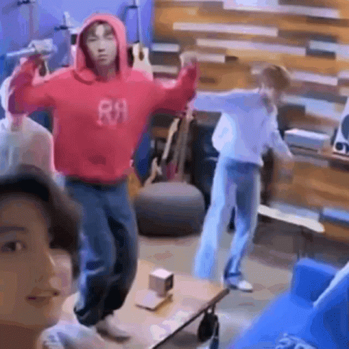 A Man In A Red Hoodie Is Holding A Microphone And Dancing In A Living Room . GIF
