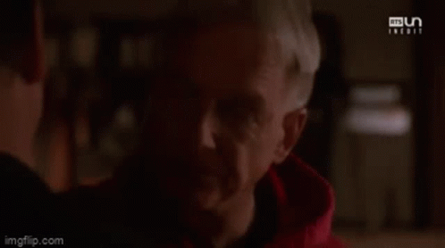 A Man In A Red Hoodie Is Looking At Another Man . GIF