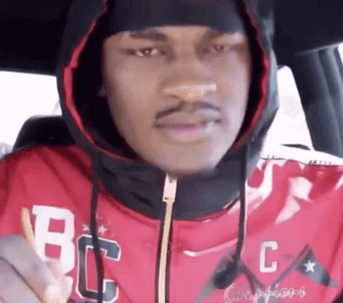 A Man In A Red Hoodie Is Sitting In The Back Seat Of A Car . GIF