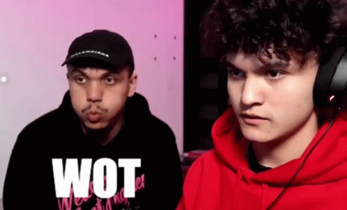 A Man In A Red Hoodie Is Standing Next To Another Man In A Black Hat . GIF