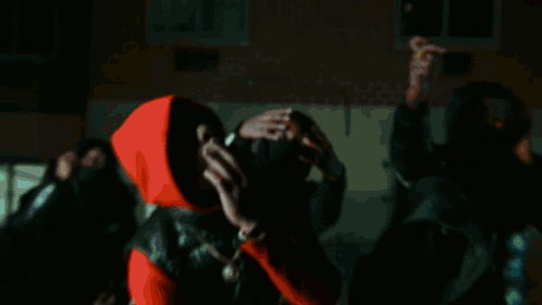 A Man In A Red Hoodie Looks Up At Something GIF