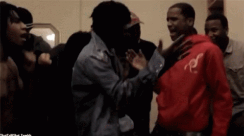 A Man In A Red Hoodie With The Letter R On It Stands In A Crowd Of People GIF