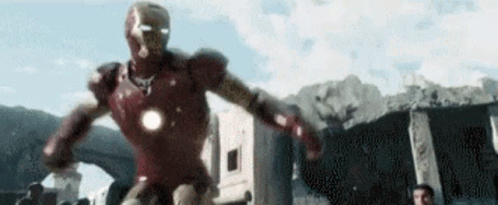 A Man In A Red Iron Man Suit Is Running Through A City . GIF
