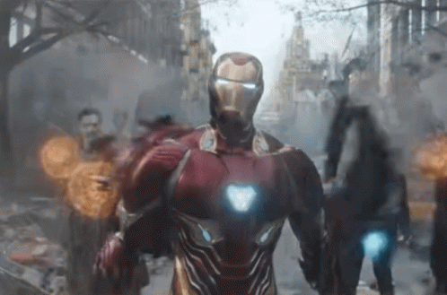 A Man In A Red Iron Man Suit Is Walking Down A City Street GIF