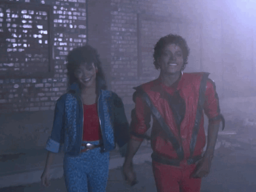 A Man In A Red Jacket And A Woman In A Blue Jacket Are Dancing GIF