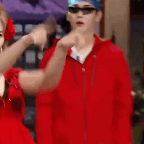 A Man In A Red Jacket And A Woman In A Red Dress Are Standing Next To Each Other In A Blurry Photo . GIF