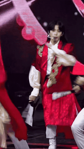 A Man In A Red Jacket And White Pants Is Dancing On A Stage GIF