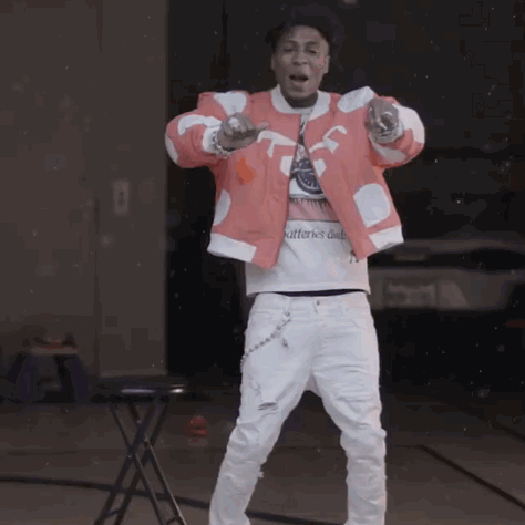 A Man In A Red Jacket And White Pants Is Standing In Front Of A Table GIF