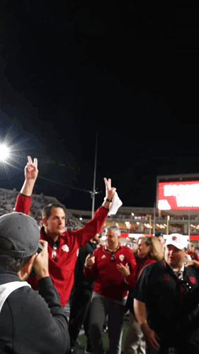 A Man In A Red Jacket Holds Up His Index Finger In The Air GIF