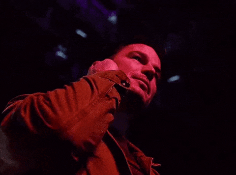 A Man In A Red Jacket Is Covering His Ears With His Hands GIF