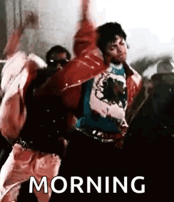 A Man In A Red Jacket Is Dancing In Front Of A Crowd With His Hands In The Air . GIF