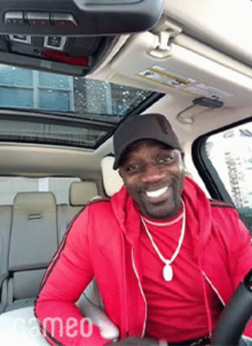 A Man In A Red Jacket Is Driving A Car GIF
