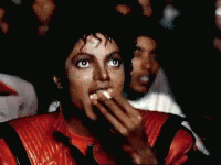 A Man In A Red Jacket Is Eating A Sandwich GIF