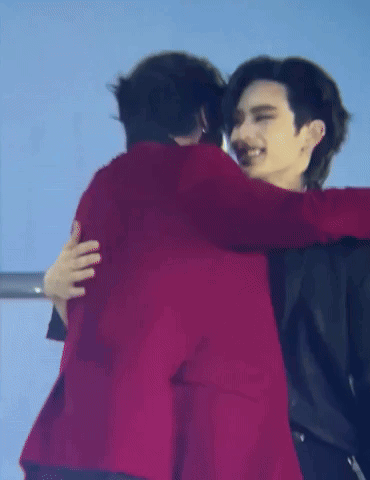 A Man In A Red Jacket Is Hugging Another Man In A Black Jacket . GIF