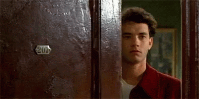 A Man In A Red Jacket Is Peeking Out From Behind A Door . GIF