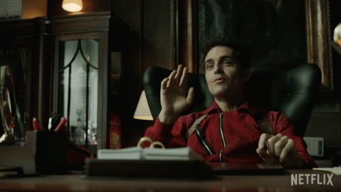 A Man In A Red Jacket Is Sitting At A Desk With Netflix Written On The Bottom GIF