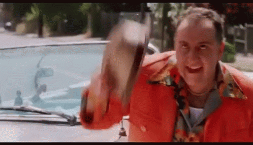 A Man In A Red Jacket Is Standing In Front Of A Car Holding A Hat . GIF