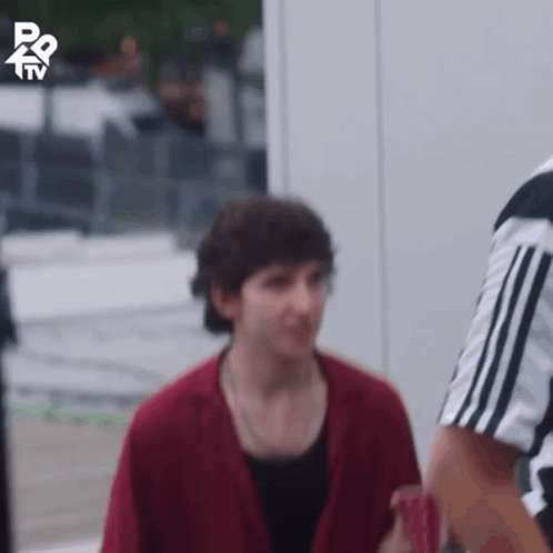 A Man In A Red Jacket Is Standing Next To A Referee In A Black And White Shirt GIF