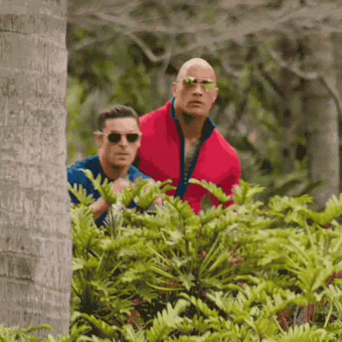 a man in a red jacket is standing next to another man in a blue shirt .