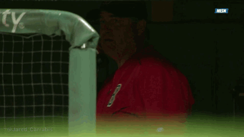 A Man In A Red Jacket Is Talking On A Cell Phone In A Dugout GIF