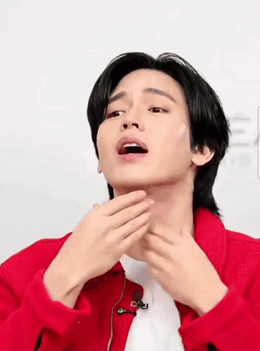 A Man In A Red Jacket Is Touching His Face GIF