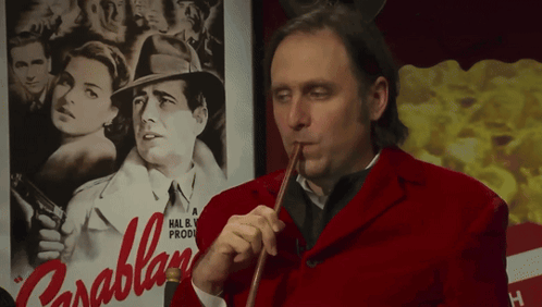 a man in a red jacket playing a violin in front of a poster for parablan