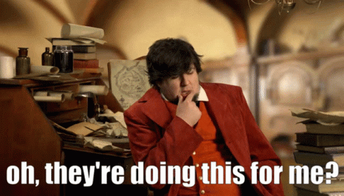 A Man In A Red Jacket Says Oh They 'Re Doing This For Me While Sitting At A Desk GIF