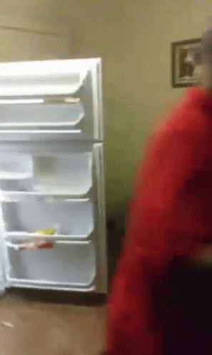 A Man In A Red Jacket Stands In Front Of An Empty Refrigerator GIF