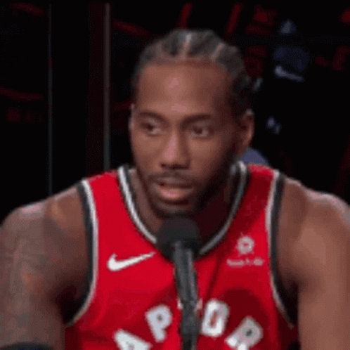 A Man In A Red Jersey Is Talking Into A Microphone . GIF