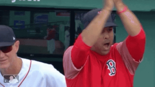 A Man In A Red Jersey With The Letter B On It Is Giving A High Five To Another Man . GIF