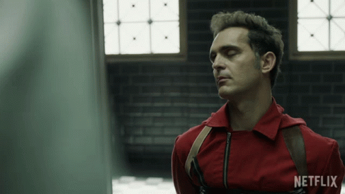 A Man In A Red Jumpsuit With A Netflix Logo On His Shirt GIF
