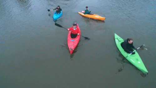 A Man In A Red Kayak Is Paddling Next To Two Other Kayaks GIF