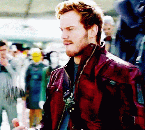 A Man In A Red Leather Jacket Stands In Front Of A Crowd Of People GIF